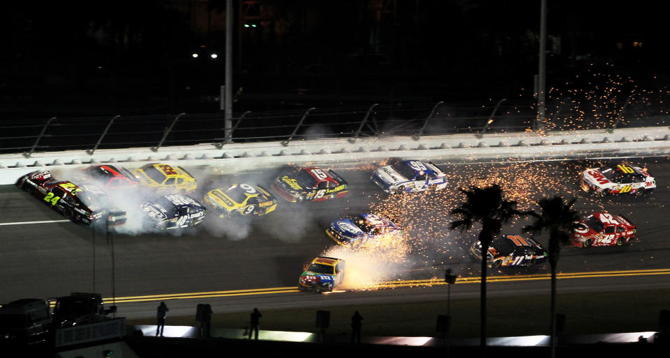 DAYTONA BEACH, FL - FEBRUARY 18: Jeff Gordon, driver of the #24 Drive to End Hunger Chevrolet, and Kurt Busch, driver of the #51 Tag Heuer Avant-Garde Chevrolet Chevrolet, and Kyle Busch, driver of the #18 M&M's Brown Toyota, crash in front of the pack during the NASCAR Budweiser Shootout at Daytona International Speedway on February 18, 2012 in Daytona Beach, Florida. (Photo by Jamie Squire/Getty Images)