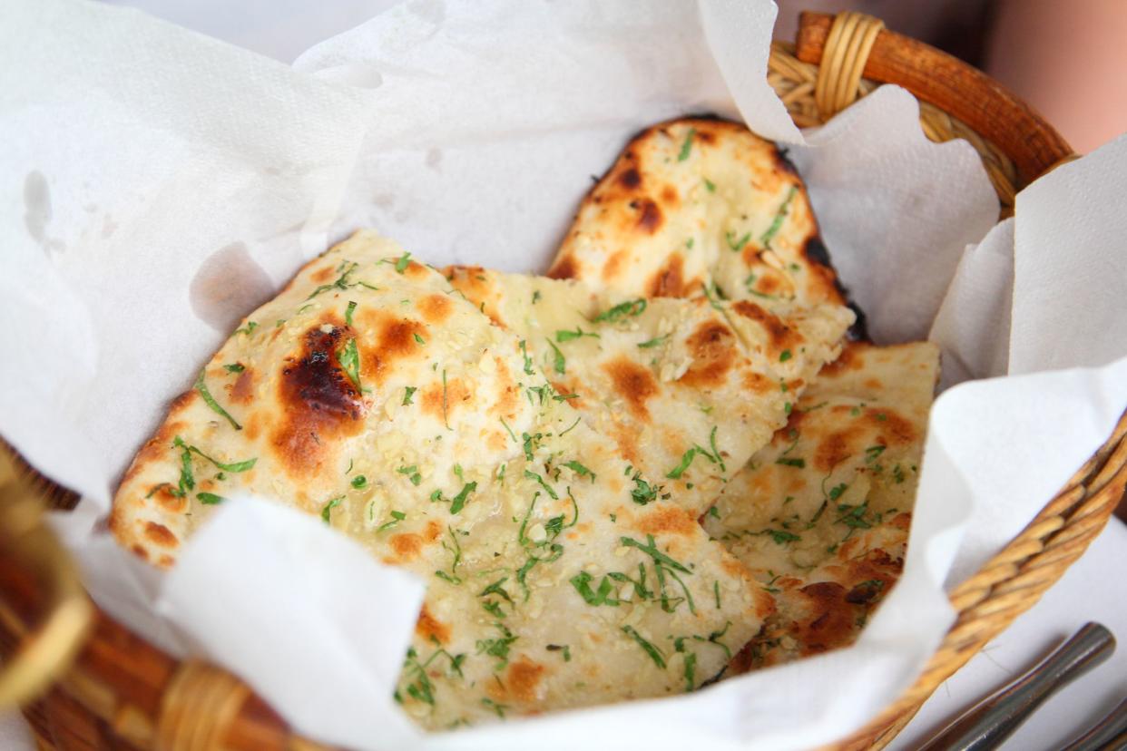 Two pieces of garlic naan bread in a basket.