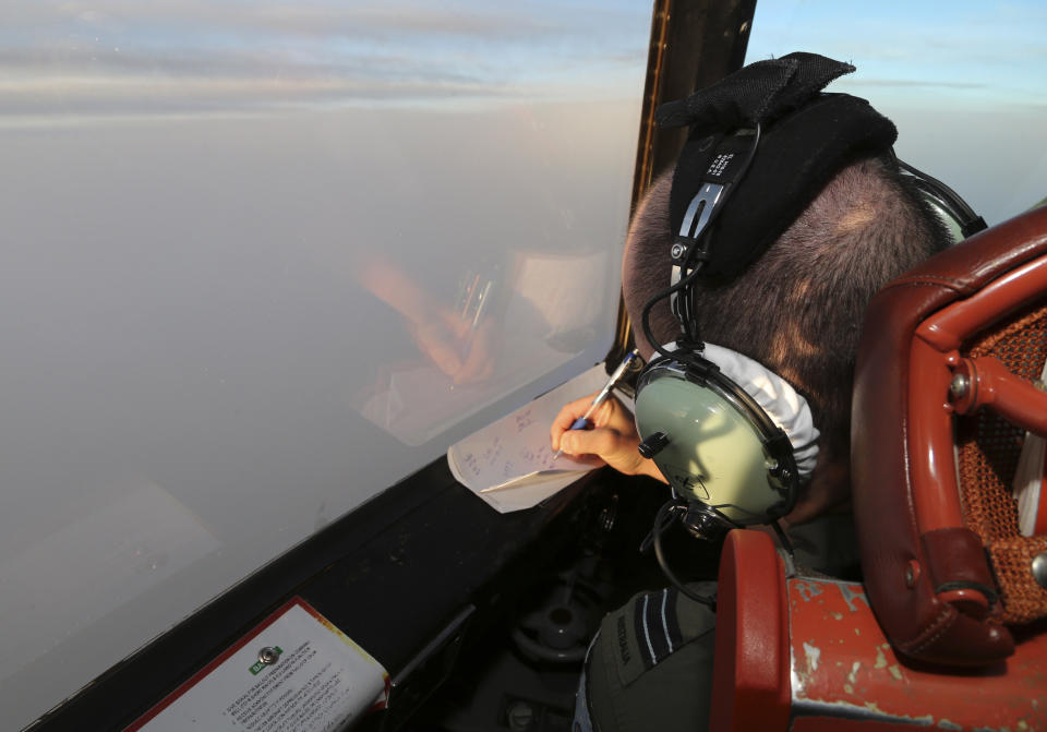 Flight Lt. Jason Nichols on board a Royal Australian Air Force AP-3C Orion, takes notes as they search for the missing Malaysia Airlines Flight MH370 in southern Indian Ocean, Australia, Saturday, March 22, 2014. Frustration grew Saturday over the lack of progress tracking down two objects spotted by satellite that might be Malaysia Airlines Flight 370, with a Malaysian official expressing worry that the search area will have to be widened if no trace of the plane is found. (AP Photo/Rob Griffith, Pool)