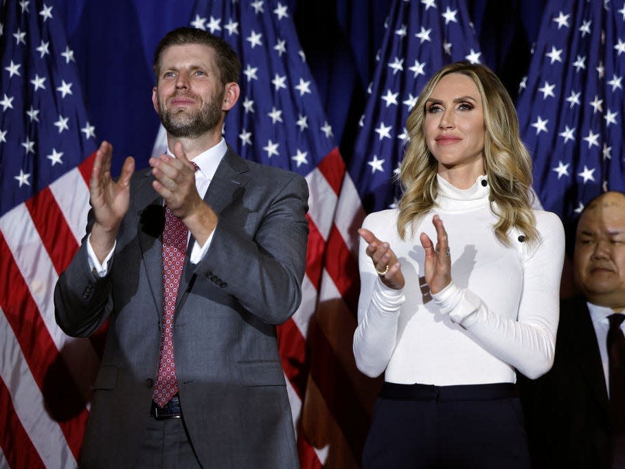 Eric Trump and Lara Trump applaud in front of American flags