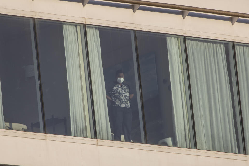 A woman wearing a mask to prevent the spread of the COVID-19 looks out of the Mein Schiff 6 cruise ship as it is docked at Piraeus port, near Athens on Tuesday, Sept. 29, 2020. Greek authorities say 12 crew members on a Maltese-flagged cruise ship carrying more than 1,500 people on a Greek islands tour have tested positive for coronavirus and have been isolated on board. (AP Photo/Petros Giannakouris)