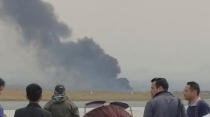 <p>People stand as smoke rises following the crash of a Bangladeshi aircraft at Kathmandu airport, Nepal March 12, 2018, in this picture grab obtained from social media video. (Photo: Nitin Keyal/via Reuters) </p>