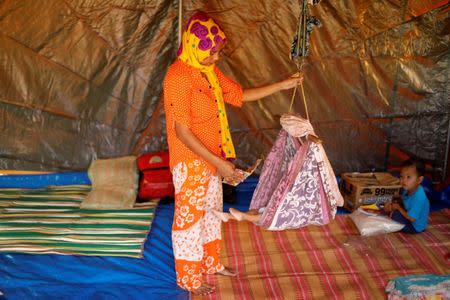 A mother bounces a baby inside her family tent at an evacuation center outside Marawi while government forces still fighting insurgents from the Maute group in Marawi, Philippines June 26, 2017. REUTERS/Jorge Silva