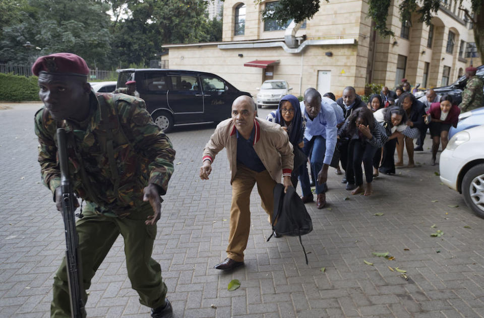 Civilians who had been hiding in buildings flee under the direction of a member of security forces (Picture: AP)