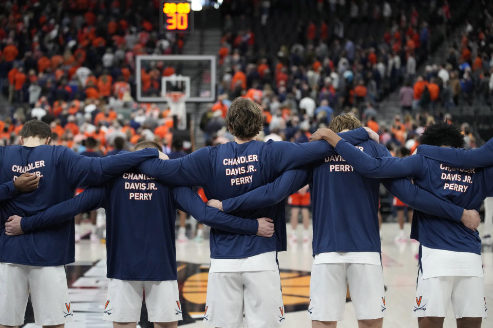 Virginia players wear shirts in honor of football players Devin Chandler, D'Sean Perry and Lavel Davis Jr. before an NCAA college basketball game against Illinois, Sunday, Nov. 20, 2022, in Las Vegas. The three (AP Photo/John Locher)