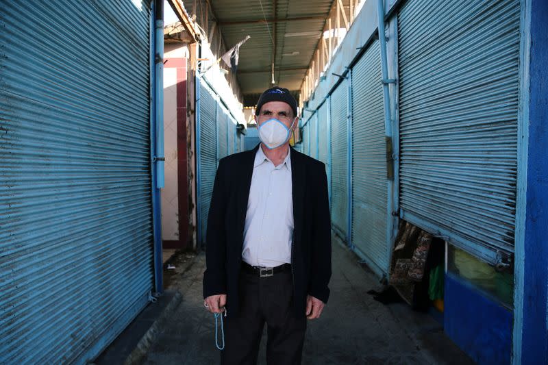 A man wearing a protective face mask, following the outbreak of coronavirus disease (COVID-19), walks next to a closed shop at a bazaar in Qom