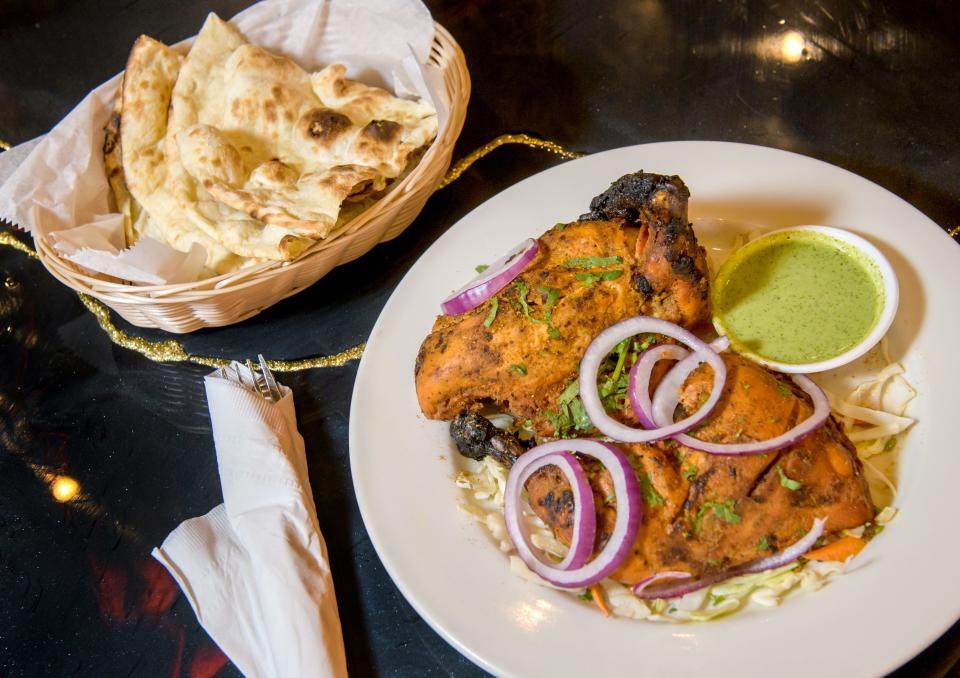 An entree of Tashan Tandoori Murgh, chicken marinated in yogurt and aromatic spices, cooked in a tandoor oven, with a basket of naan flatbread on the side, at the new Indian restaurant Bollywood Bites in downtown Peoria. A tandoor oven is a traditional clay oven used for centuries in the Indian and Asian subcontinent.