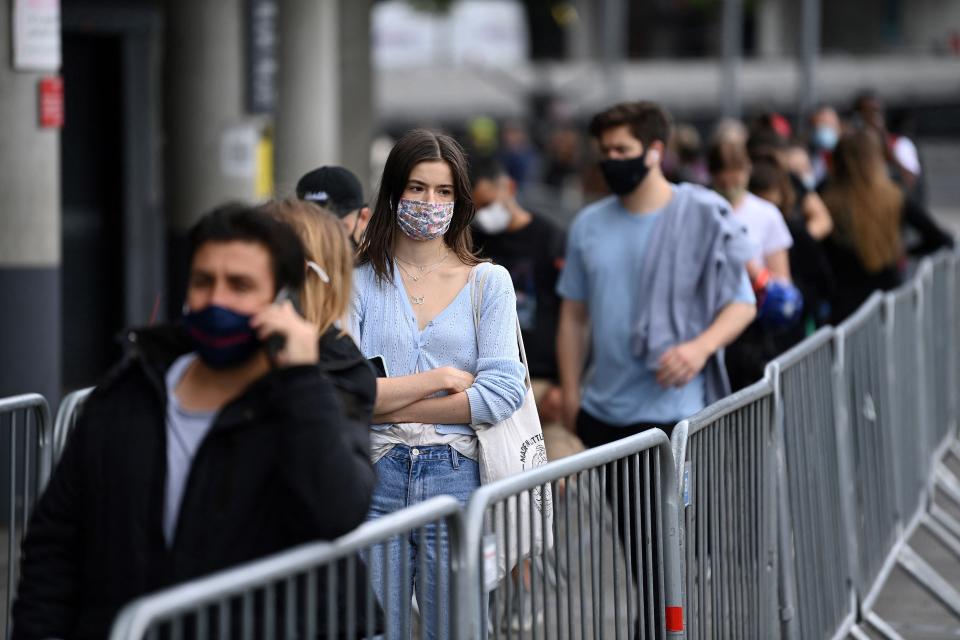 Members of the public queue to receive a dose of a Covid-19 vaccine outside a temporary vaccination centre set up a the Emirates Stadium (AFP via Getty Images)