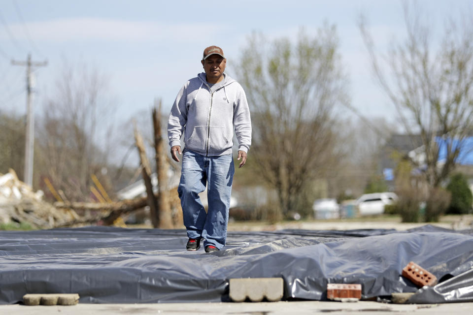 In this March 26, 2020, photo, Jose Cojom walks across what is left of his home after it was destroyed by a tornado in Cookeville, Tenn. Like thousands of other Middle Tennesseans, Cojom's life has been upended by back-to-back disasters. Residents still reeling from the deadly twisters of March 3 now have to confront life in the age of coronavirus. (AP Photo/Mark Humphrey)