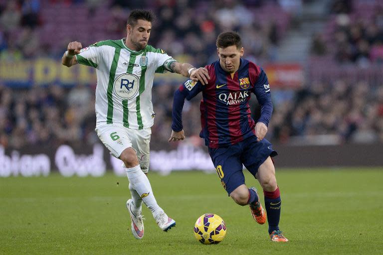 Cordoba's midfielder Luis Eduardo "luso" Delgado vies with Barcelona's Argentinian forward Lionel Messi (right) during a Spanish league match at the Camp Nou stadium in Barcelona on December 20, 2014