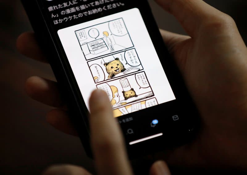 Japanese manga artist Kamentotsu shows his his four-panel strip comic 'Koguma's Cake Shop' on his smartphone at his workspace in Tokyo