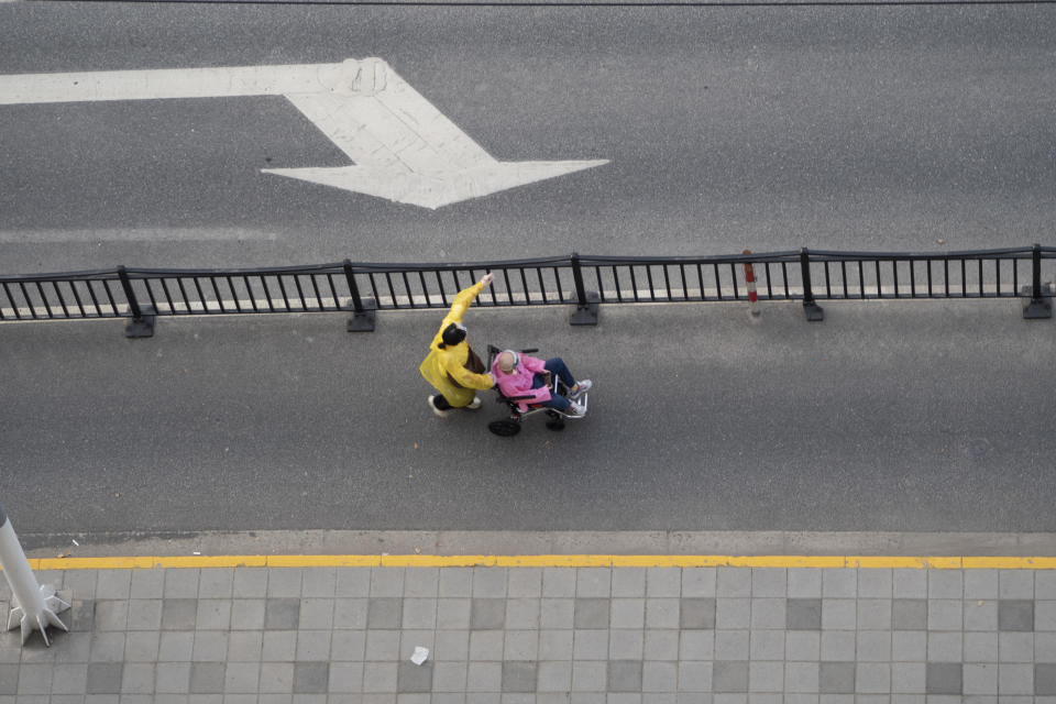 A pedestrian pushes an elderly man in a wheelchair on a street in Shanghai, China, April 12, 2022, after a city-wide COVID-19 lockdown was lifted for several neighborhoods where the virus was no longer being detected, and amid mounting anger among residents over the strict control measures. / Credit: Costfoto/Future Publishing/Getty