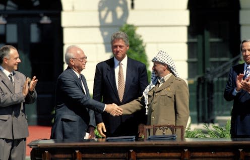 <span class="caption">Yitzhak Rabin of Israel and Yasser Arafat of the PLO shake hands at the White House South Lawn after signing the Peace Accords, President Bill Clinton looks on.</span>