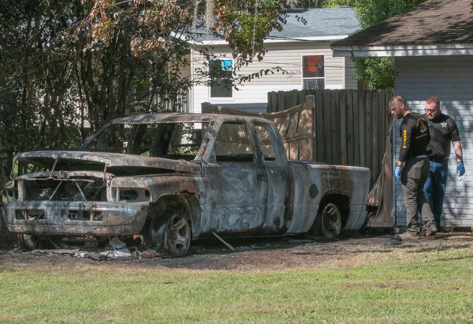 Members of the Polk County Sheriff's Office crime scene unit look over a burned pickup truck Monday morning at a home on North Socrum Loop Road in North Lakeland where four people were killed and an 11-year-old girl was severely wounded in a mass shooting on Sunday.