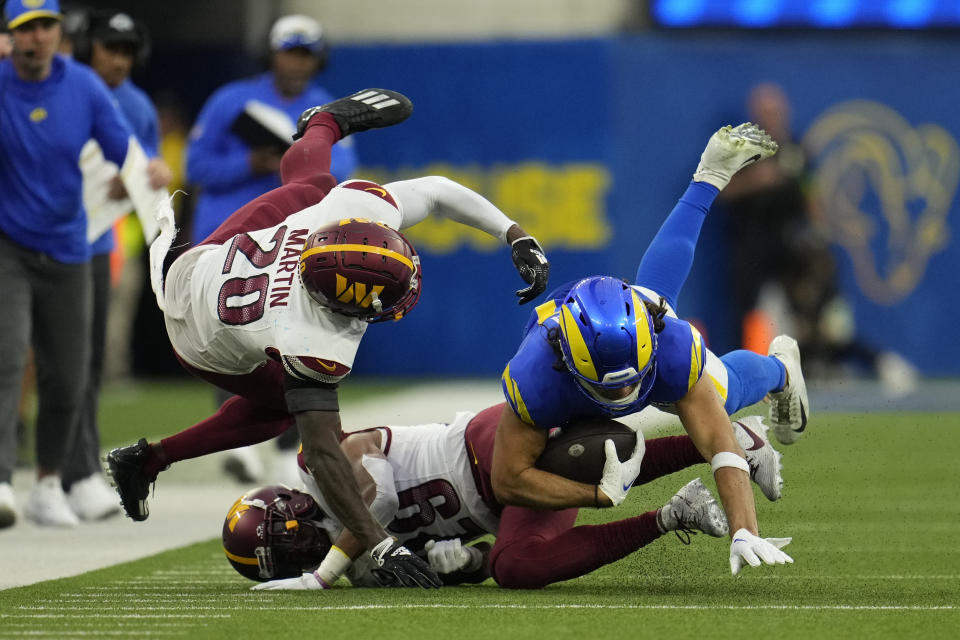 Los Angeles Rams wide receiver Puka Nacua, right, is tackled by Washington Commanders safety Jartavius Martin (20) and cornerback Kendall Fuller (29) during the second half of an NFL football game Sunday, Dec. 17, 2023, in Inglewood, Calif. (AP Photo/Marcio Jose Sanchez)