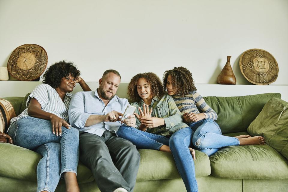 family sitting on couch in living room looking at smart phone