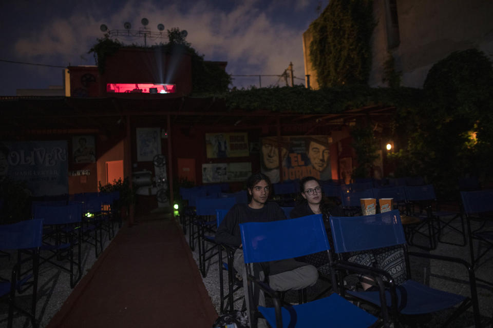 In this Monday June 1, 2020 photo, Panos and Marianna, the only customers at the Zephyros open-air cinema that specializes in films from past decades in the Petralona district in central Athens, are seen on the first day the cinema opened after the easing of Greece's coronavirus lockdown. (AP Photo/Petros Giannakouris)