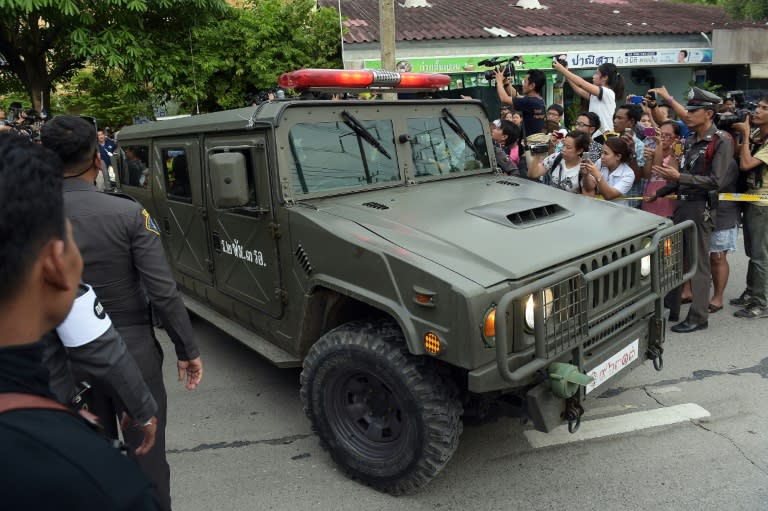 Policemen make way for an armored military car, part of a convoy carrying a suspect in the August 17 Bangkok shrine bombing, on August 29, 2015