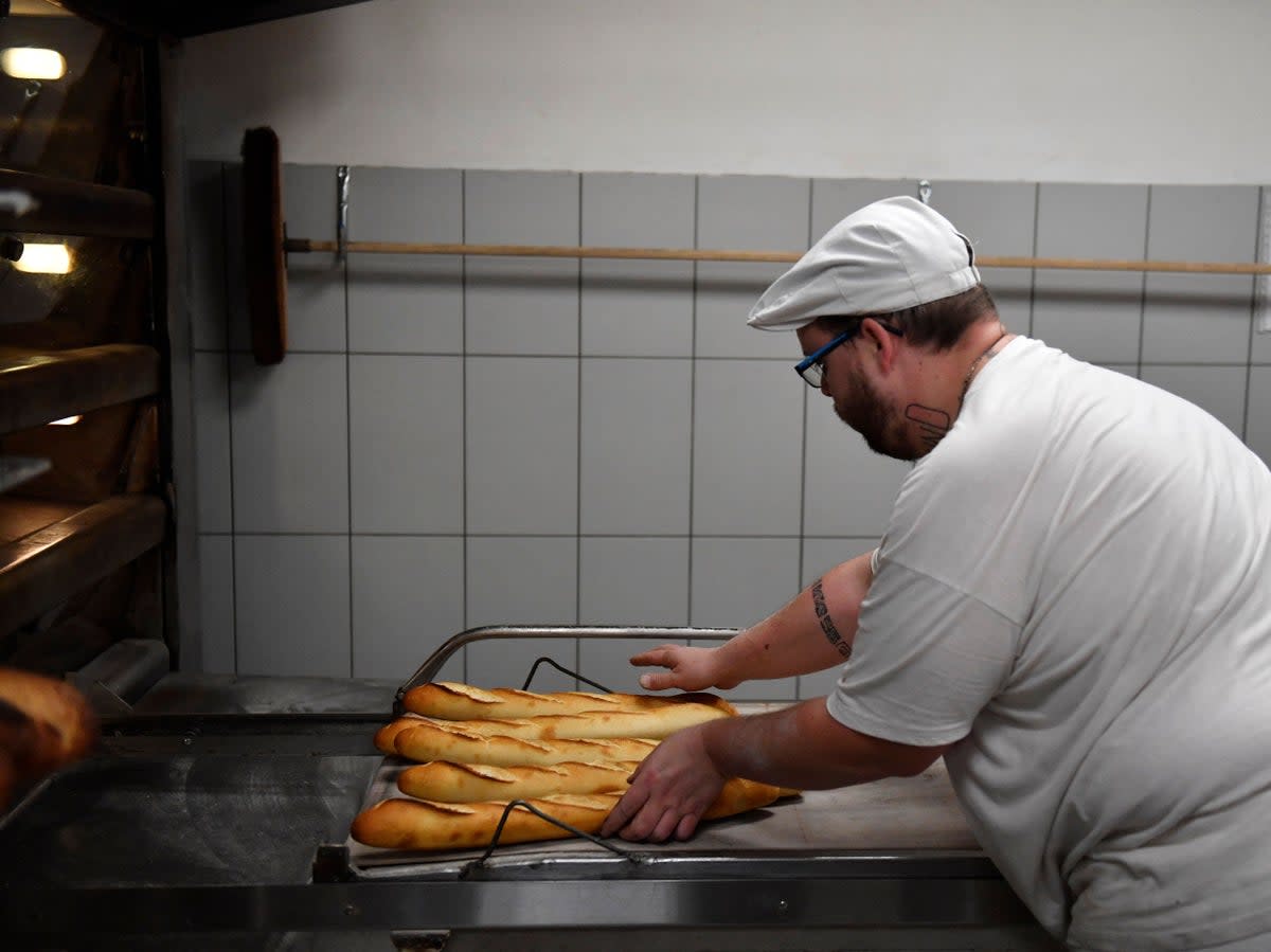 A baker prepares baguettes in a bakery in Brou near Chartres on 1 December 2022 (JULIEN DE ROSA/AFP via Getty Images)