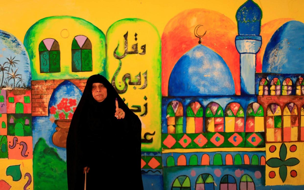 An Iraqi woman shows her ink-stained finger after casting her vote at a polling station - REUTERS