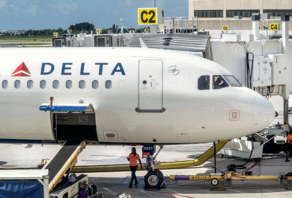 A Delta Airlines flight crew waits for passengers to board for departure Friday at Palm Beach International Airport.