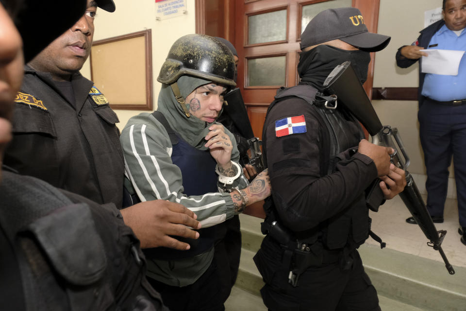 Rapper Daniel Hernandez, known as Tekashi 6ix9ine, is escorted by police to a different area of the court at the Palace of Justice in Santo Domingo, Dominican Republic, Thursday, Jan. 25, 2024. Authorities arrested the rapper on Jan. 17 on charges of domestic violence. (AP Photo/Ricardo Hernandez)