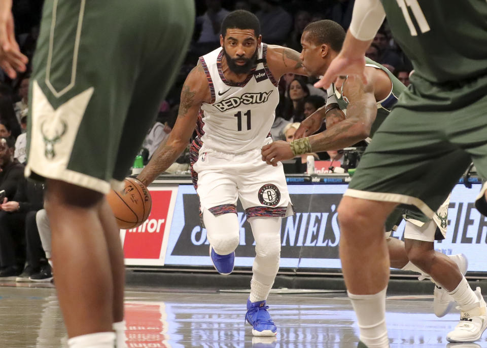 Brooklyn Nets guard Kyrie Irving, center, drives to the basket past Milwaukee Bucks Eric Bledsoe, right, during a NBA basketball game, Saturday Jan. 18, 2020 in New York. (AP Photo/Bebeto Matthews)