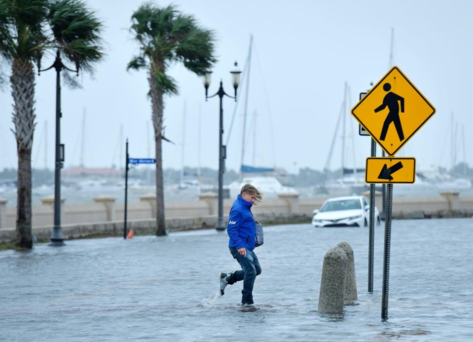 A pedestrian makes their way across a flooded section of Avenida Menendez in St. Augustine, Fla., after storm-driven high tides flooded low-lying areas of the city.