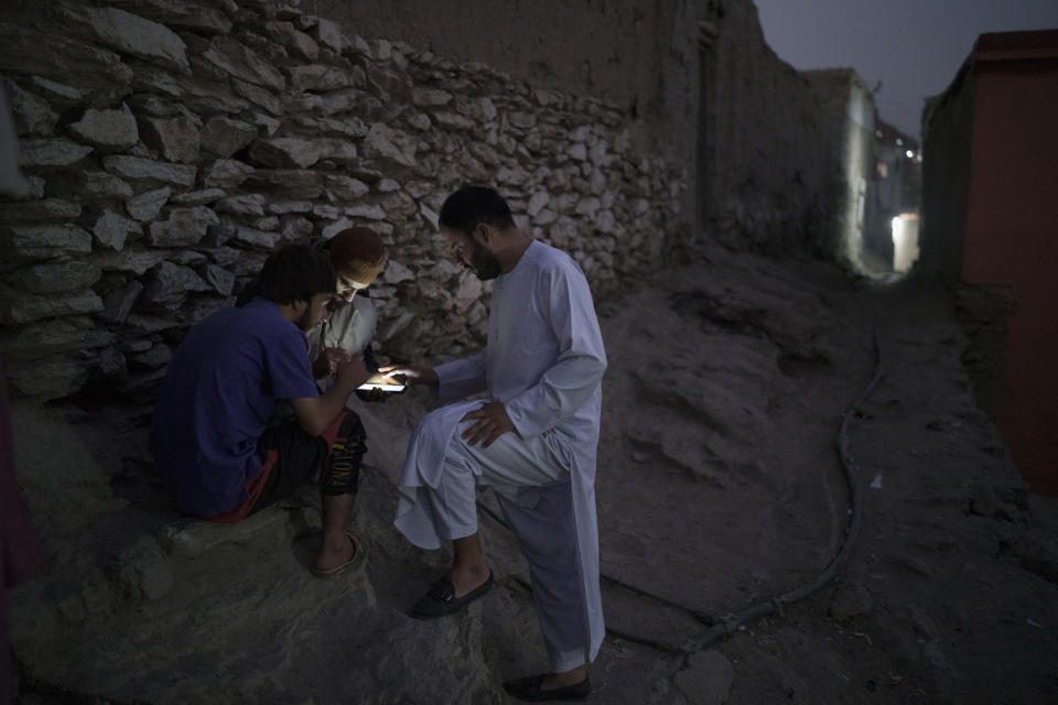 Afghans play games on a cellphone outside their home in Kabul, Afghanistan, Saturday, Sept. 11, 2021. (AP Photo/Felipe Dana)