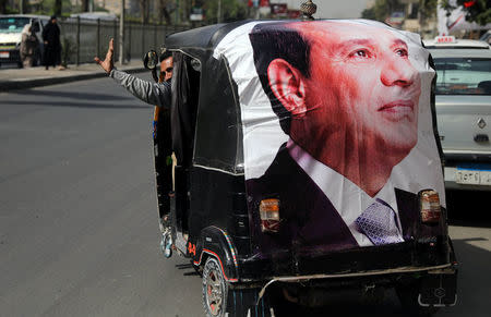 A man gestures as he rides a motorized vehicle showing a poster of Egyptian President Abdel Fattah al-Sisi during the second day of the presidential election in Cairo, Egypt, March 27, 2018. REUTERS/Ammar Awad