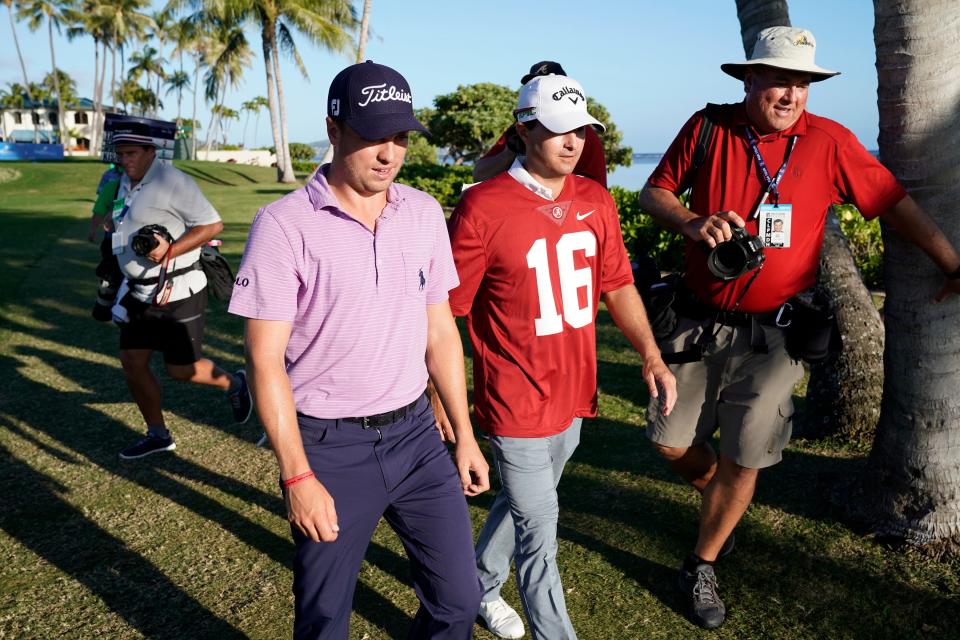 As media members scramble around them, Justin Thomas, left, walks with pairing partner Kevin Kiser, who is wearing an Alabama football jersey, onto the 17th green during the first round of the Sony Open golf tournament Thursday, Jan. 11, 2018, in Honolulu. Kisner, who lost a bet to Thomas over the outcome of the college football championship game between Georgia and Alabama, had to wear the Alabama jersey during play on the 17th. Kisner played golf at Georgia. (AP Photo/Marco Garcia)