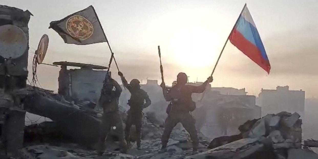 Wagner mercenary group fighters wave flags of Russia and Wagner group on top of a building in an unidentified location, in the course of the Russia-Ukraine conflict, in this still image obtained from a video released on May 20, 2023.
