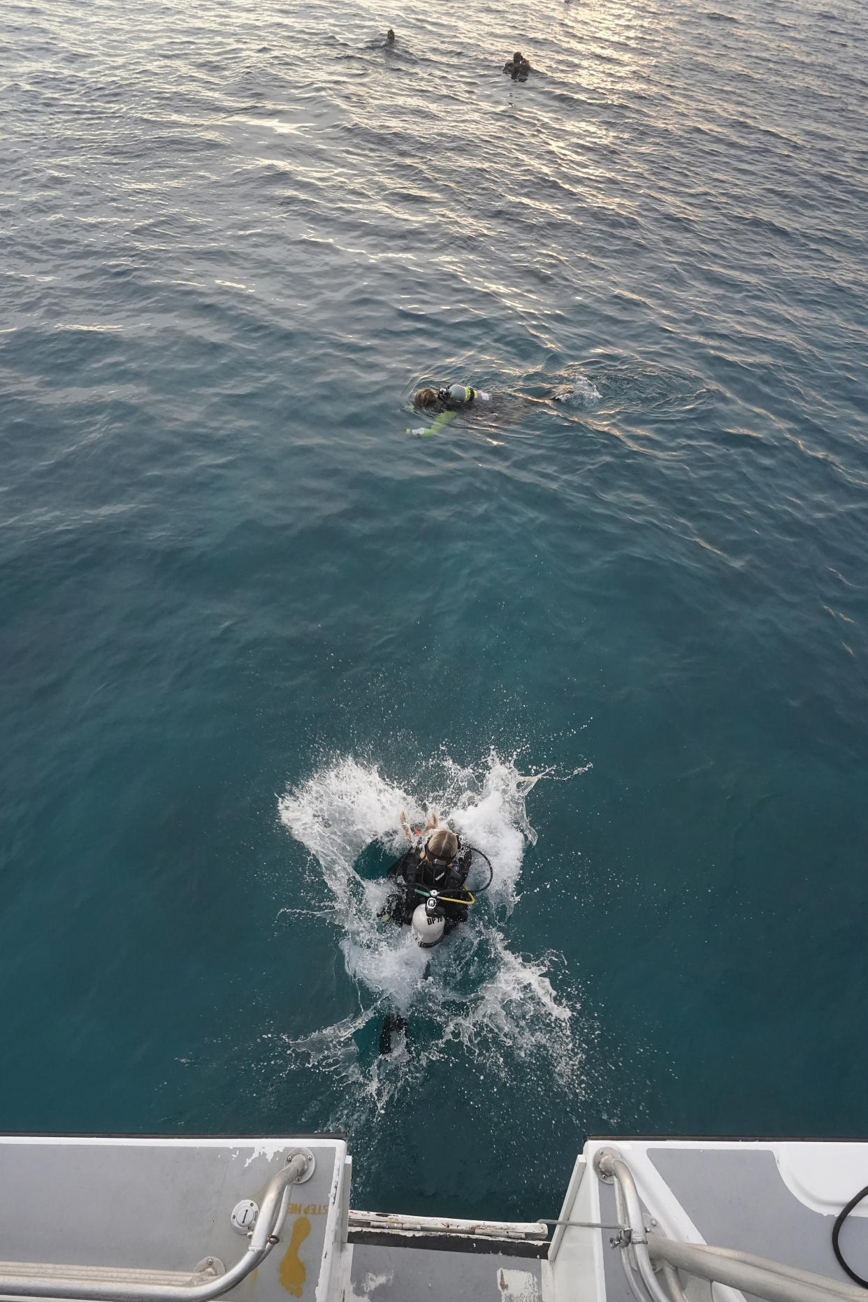 University of Miami's Rosenstiel School of Marine & Atmospheric Science student Avery Boals, 21, foreground, leaps in the water as she and other divers prepare for a night dive to check on coral spawning, Monday, Aug. 15, 2022, in Key Biscayne, Fla. A group of students and scientists were hoping to observe the coral spawn and collect their eggs and sperm, called gametes, to take back to the lab to hopefully fertilize and create new coral that will later be transplanted to help repopulate part of the Florida Reef Tract. (AP Photo/Wilfredo Lee)