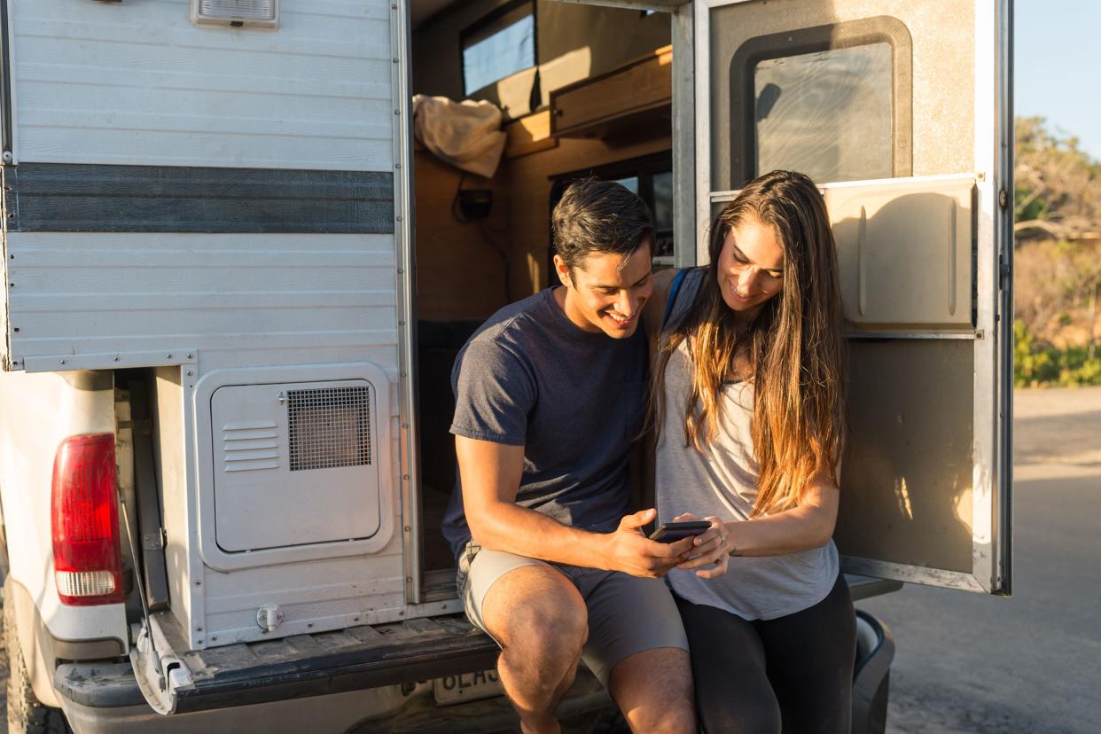 couple looking at phone in back of RV looking for place to boon-dock