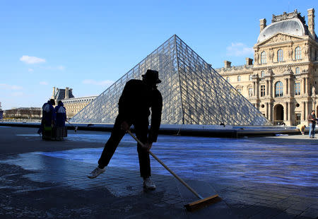 French artist JR works in the courtyard of the Louvre Museum near the glass pyramid designed by Ieoh Ming Pei as the Louvre Museum celebrates the 30th anniversary of its glass pyramid in Paris, France, March 26, 2019. REUTERS/GonzaloÊFuentes