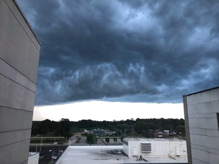 Dramatic storm clouds gather over a landscape with buildings on the horizon