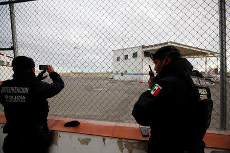 Federal police officers stand at a fence surrounding a private landing strip, as signs of increased security are seen next to the international airport in Ciudad Juarez, Mexico, January 19, 2017. REUTERS/Jose Luis Gonzalez