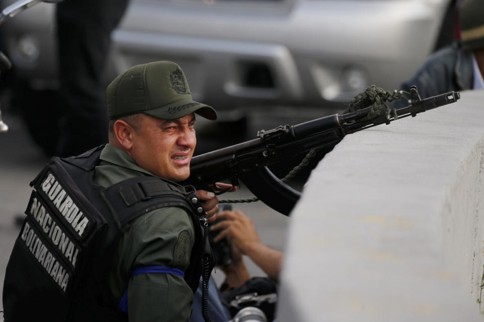 Un miembro armado de la Guardia Nacional Bolivariana que se está rebelando contra el gobierno del presidente de Venezuela, Nicolás Maduro, se cubre en un paso elevado afuera de la base aérea militar de La Carlota, donde las tropas leales se encuentran en Caracas, Venezuela, el martes 30 de abril de 2019. (AP Foto / Fernando Llano)