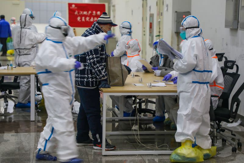 Medical workers in protective suits receive a patient at the Wuhan International Conference and Exhibition Center