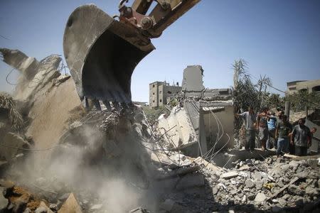 Palestinians gather as rescue workers search for victims from under the rubble of a house, which witnesses said was destroyed by an Israeli air strike, in Beit Lahiya in the northern Gaza Strip August 25, 2014. REUTERS/Mohammed Salem