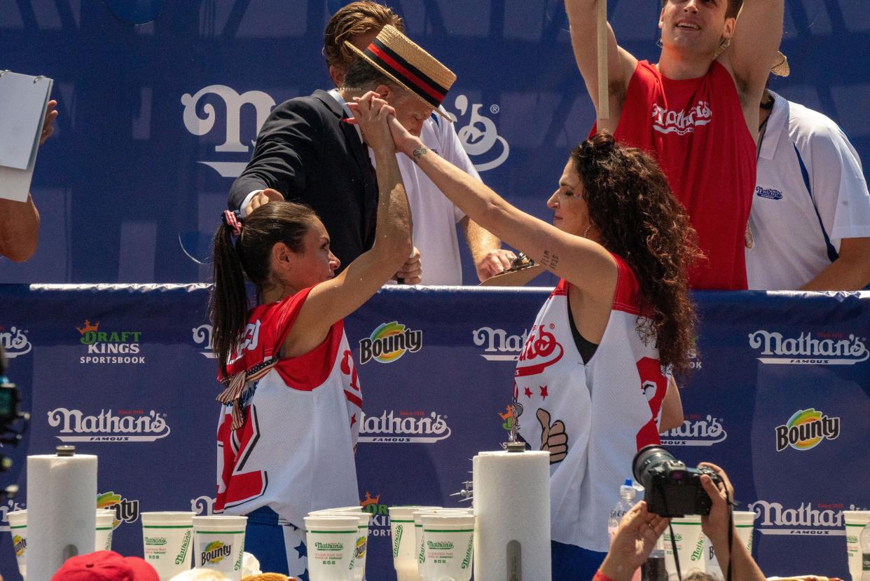Competitive eaters Michelle Lesco (L), the new women's champion, and second-place winner Sarah Rodriguez (R) high-five each other at the 2021 Nathan's Famous 4th Of July International Hot Dog Eating Contest on July 4, 2021, in New York City.