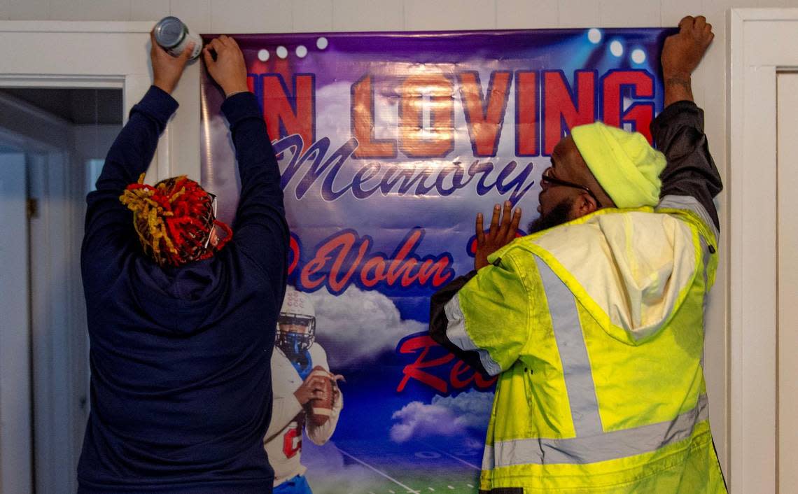DeShawn Reese, left, and Vershawn Dudley hang a poster honoring their late son, DeVohn Dudley-Reese, in Reese’s home on Tuesday in Kansas City. Dudley-Reese, a 16-year-old junior at William Chrisman High School, was killed alongside 18-year-old Jazion Sanders on Nov. 27 in Kansas City.