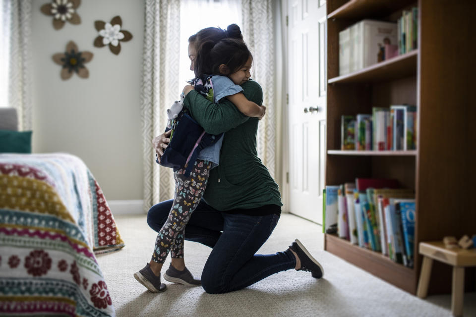 A woman hugging a small child in the child's bedroom