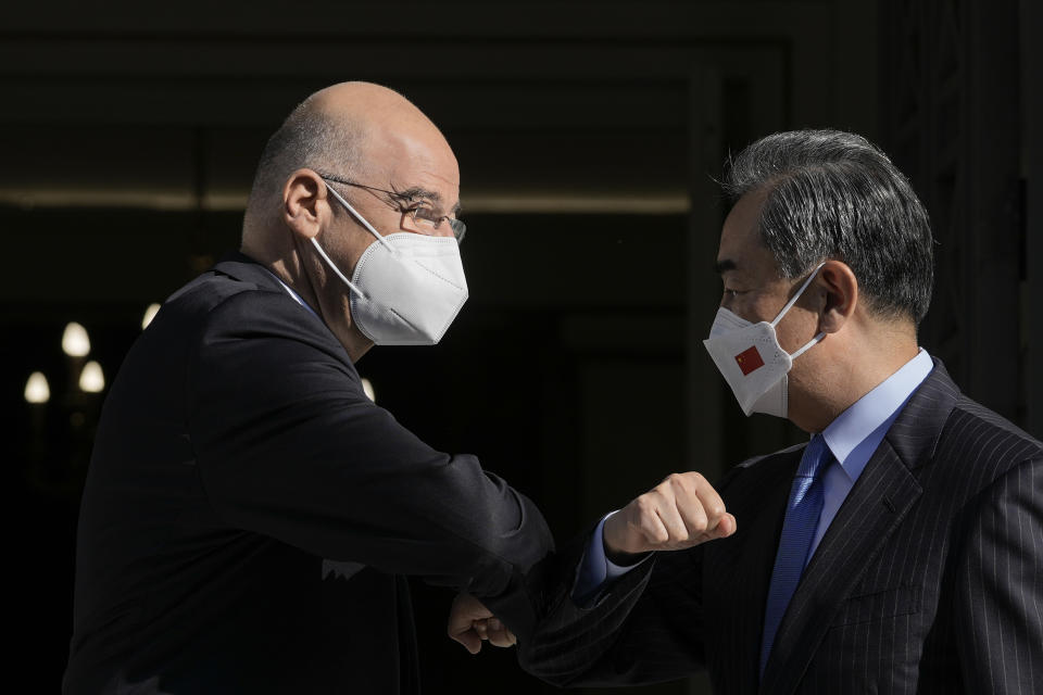 Greece's Foreign Minister Nikos Dendias, left, and his Chinese counterpart Wang Yi touch elbows and wear protective face masks to curb he spread of COVID-19 prior to their meeting, in Athens, on Wednesday, Oct. 27, 2021. (AP Photo/Petros Giannakouris)