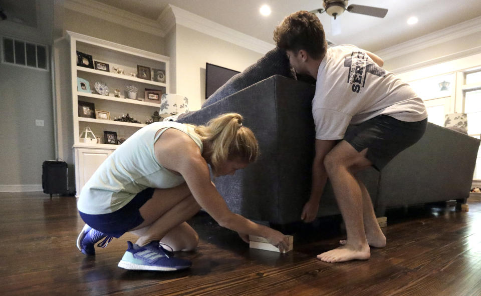 Tiffany Favre, left, and her son, Brandon, use blocks to raise their couch off the floor Friday, July 12, 2019, in Baton Rouge, La., ahead of Tropical Storm Barry. The National Weather Service in New Orleans says water is already starting to cover some low lying roads as Tropical Storm Barry approaches the state from the Gulf of Mexico. (AP Photo/David J. Phillip)