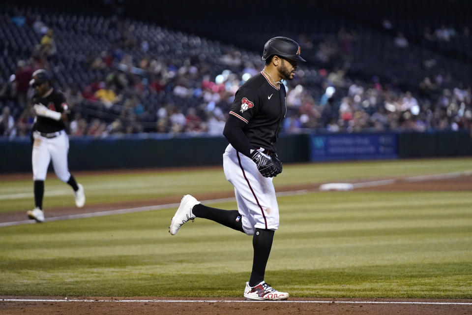 Arizona Diamondbacks' Tommy Pham, right, jogs to first base after drawing a bases-loaded walk against the Colorado Rockies as Diamondbacks' Geraldo Perdomo, left, heads to home plate to score a run during the fourth inning of a baseball game Wednesday, Sept. 6, 2023, in Phoenix. (AP Photo/Ross D. Franklin)