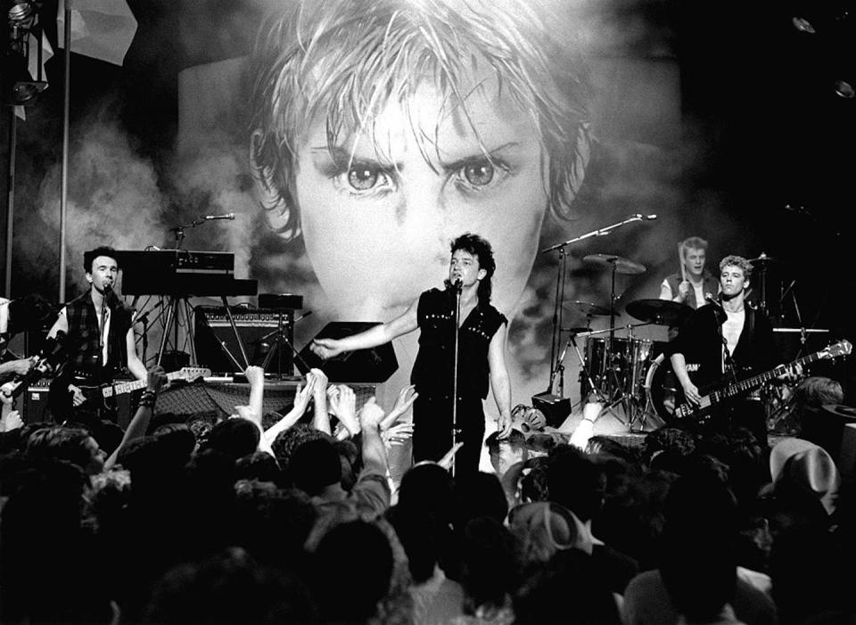 U2 performs on a television show in 1983, with an illustration from the cover of its ‘War’ album behind it. <a href="https://www.gettyimages.com/detail/news-photo/the-edge-bono-larry-mullen-jnr-adam-clayton-performing-live-news-photo/85238270?adppopup=true" rel="nofollow noopener" target="_blank" data-ylk="slk:Erica Echenberg/Redferns via Getty Images;elm:context_link;itc:0;sec:content-canvas" class="link ">Erica Echenberg/Redferns via Getty Images</a>