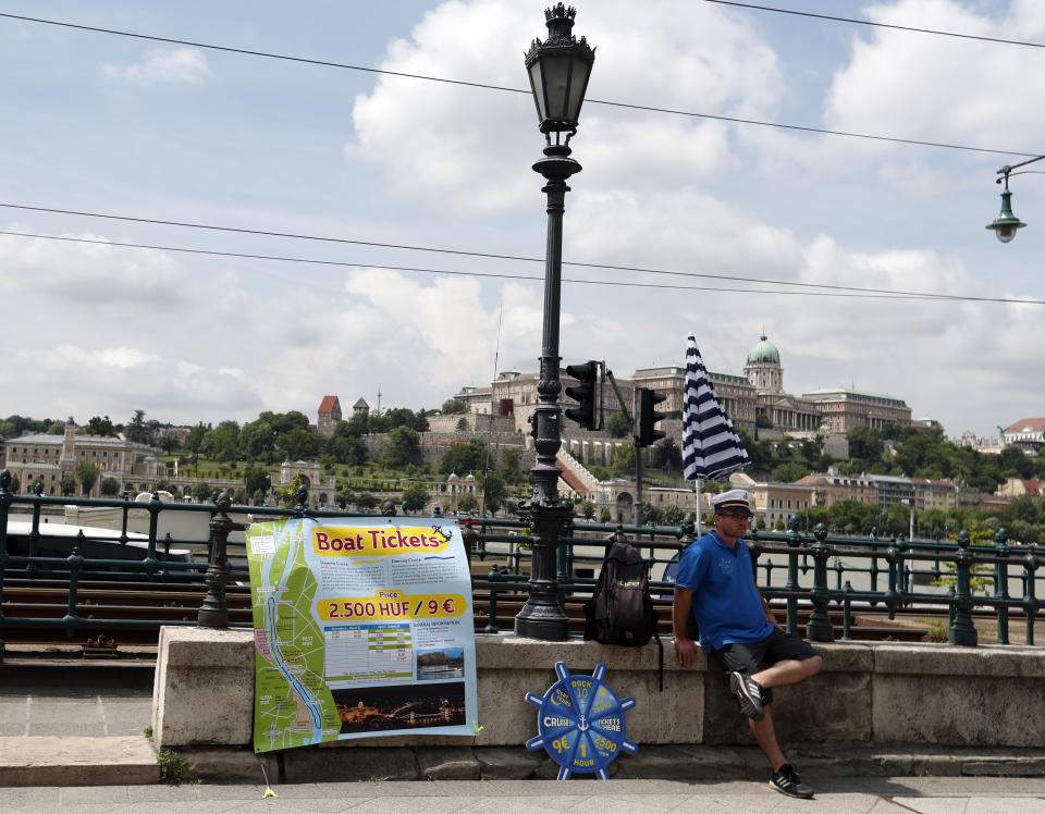 In this photo taken on Wednesday, June 5, 2019, a man sells tour boat tickets near the Danube River in Budapest, Hungary. A tourism boom in the Hungarian capital has led to major congestion on the river flowing through the city, with sightseeing boats and floating hotels competing for better positions in front of spectacular neo-Gothic buildings, ornate bridges and churches lining the Danube. (AP Photo/Laszlo Balogh)