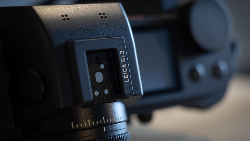 Leica SL3 camera on a wooden surface against a blue background