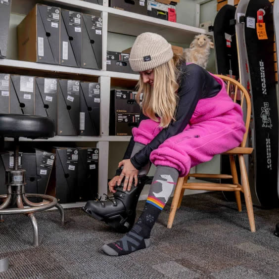 Woman shows off socks while booting up for skiing.